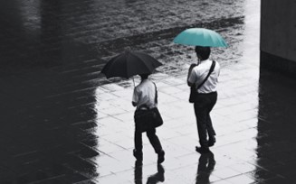 zwei personen gehen im regen mit schirm